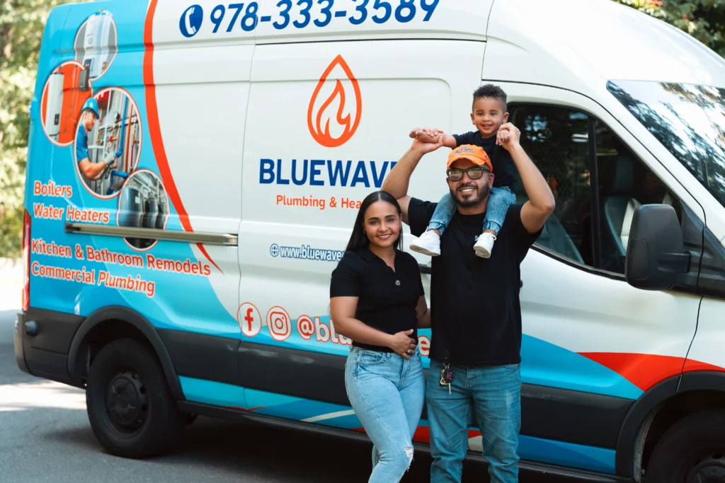 A family of three poses in front of a BLUEWAVE Plumbing & Heating van with company branding and contact information visible on the vehicle.